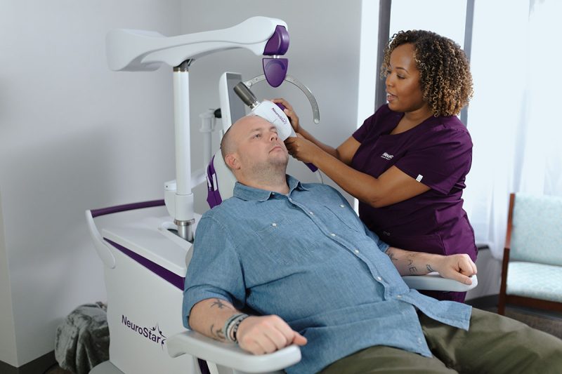 Patient sitting in NeuroStar chair with technician.